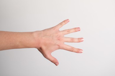 Photo of Woman with visible hand veins on light grey background, closeup