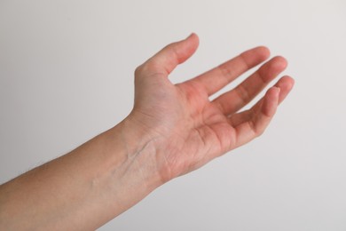 Photo of Woman with visible hand veins on light grey background, closeup