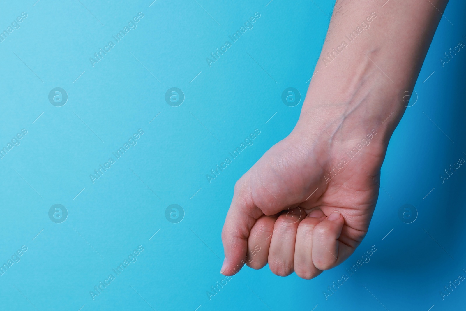 Photo of Woman with visible hand veins on light blue background, closeup. Space for text