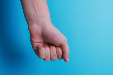 Photo of Woman with visible hand veins on light blue background, closeup