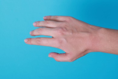 Photo of Woman with visible hand veins on light blue background, closeup