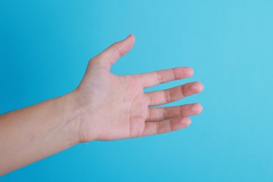 Photo of Woman with visible hand veins on light blue background, closeup