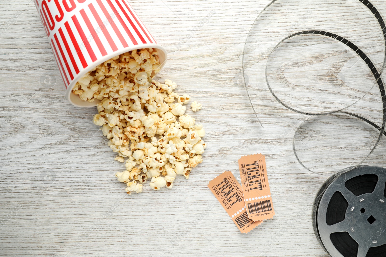 Photo of Tasty popcorn, tickets and film reel on white wooden background, flat lay