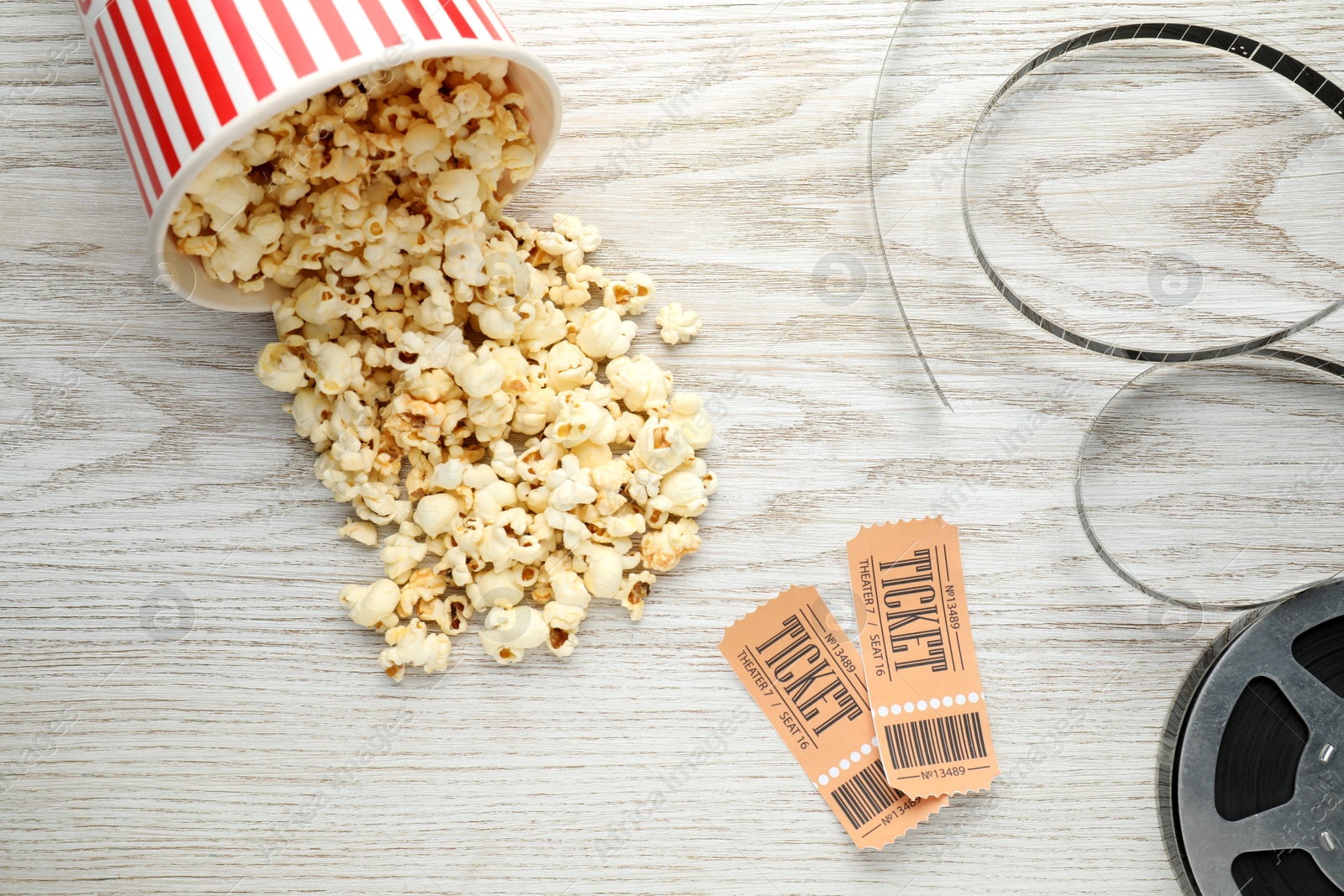 Photo of Tasty popcorn, tickets and film reel on white wooden background, flat lay