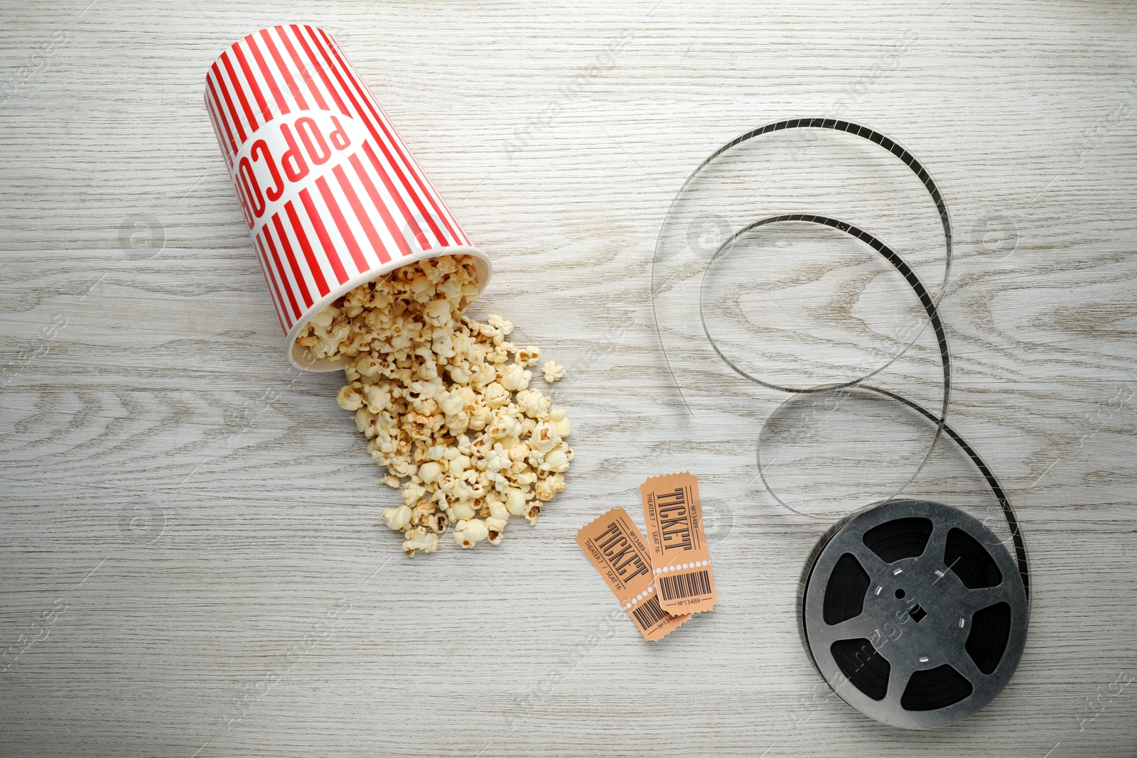 Photo of Tasty popcorn, tickets and film reel on white wooden background, flat lay