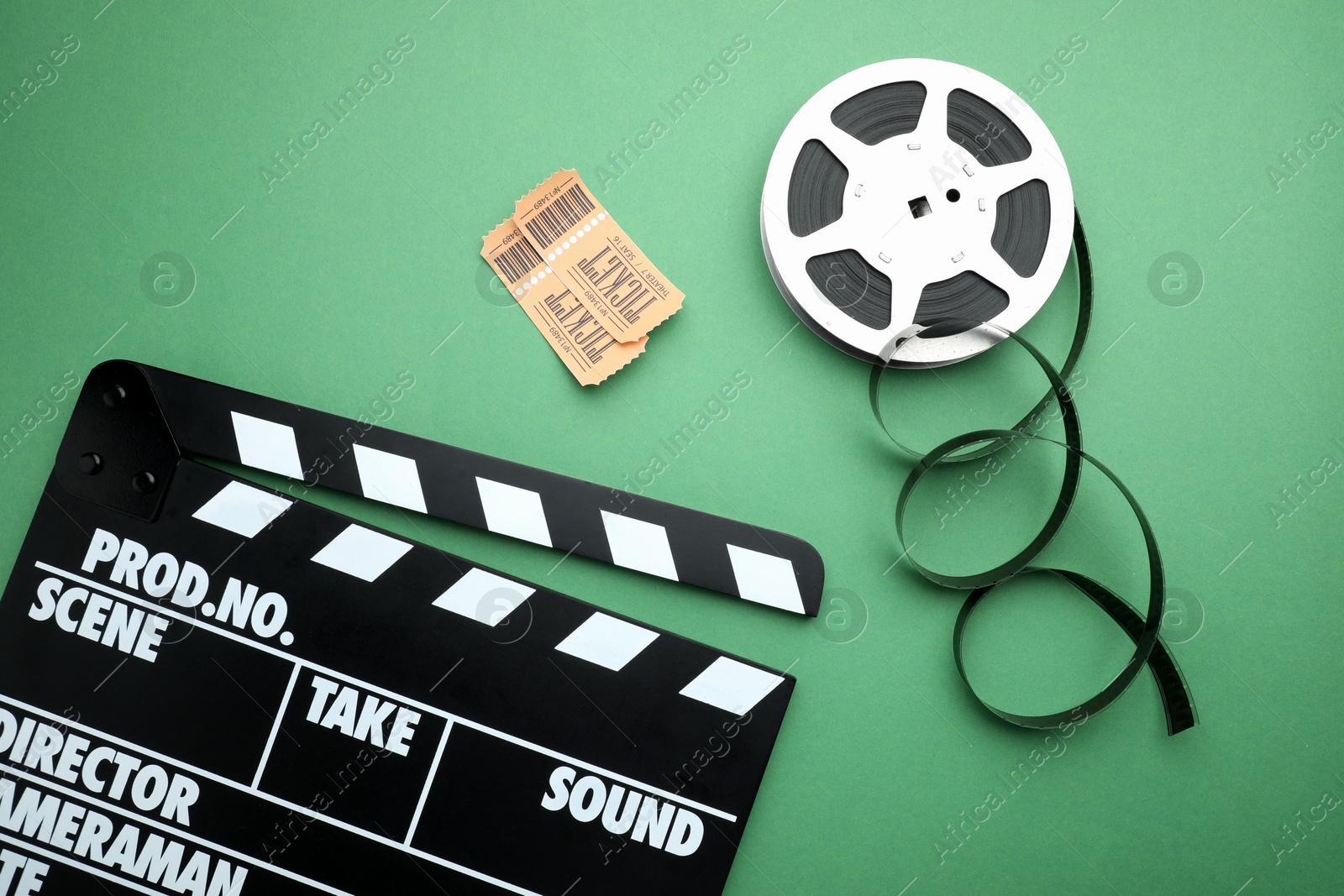 Photo of Movie clapper, tickets and film reel on green background, flat lay