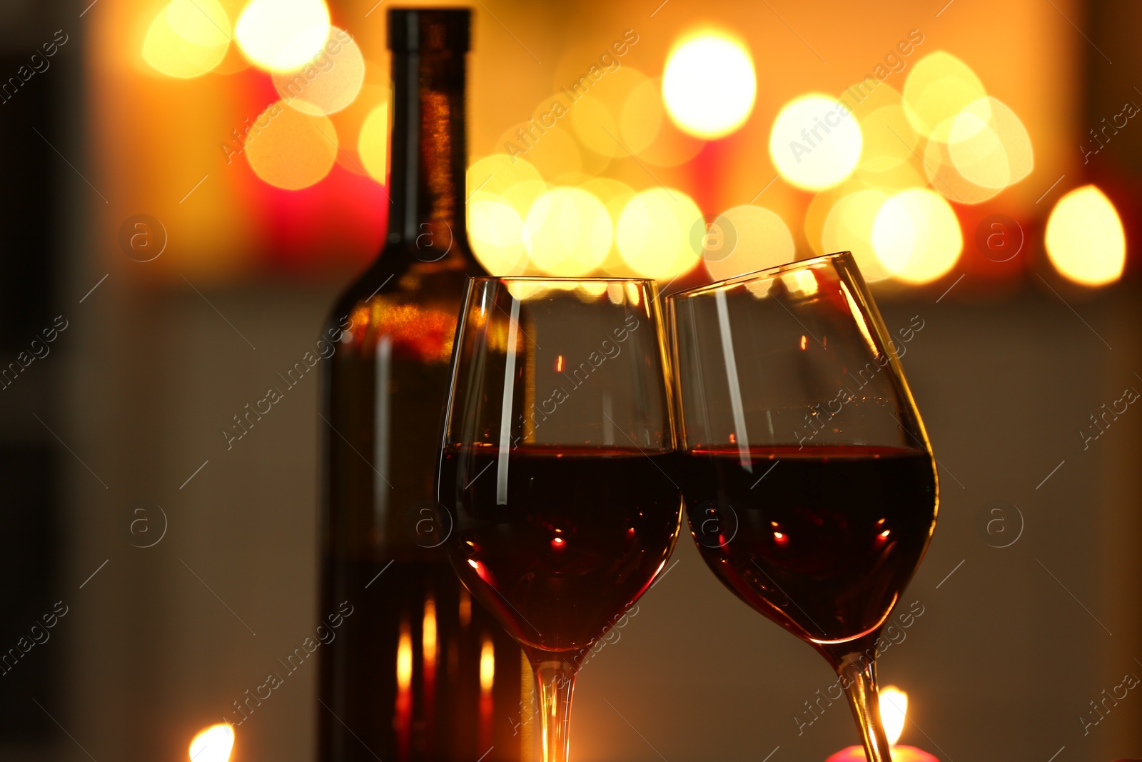 Photo of Glasses of red wine against blurred lights, closeup. Romantic dinner