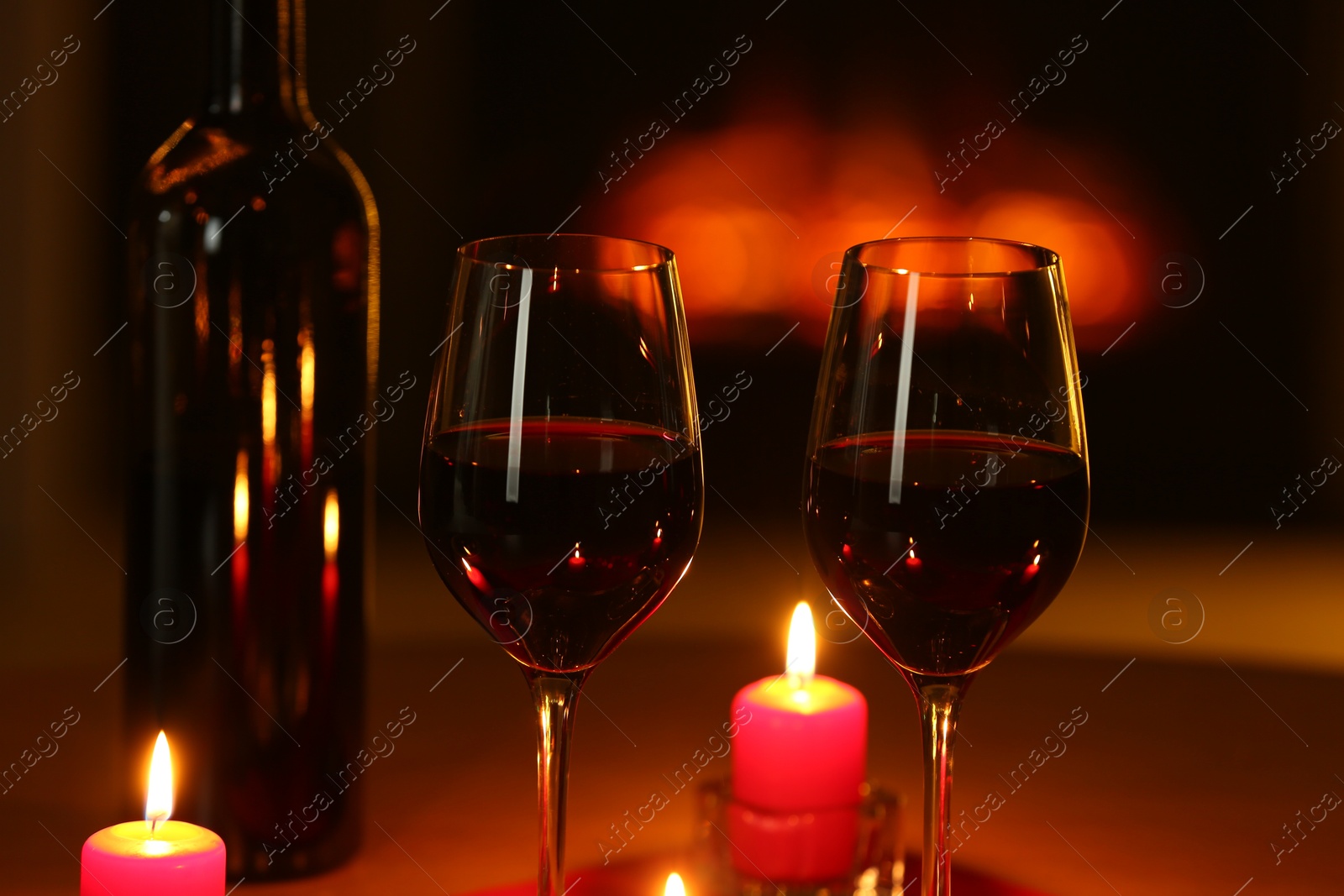 Photo of Glasses of red wine and burning candles on table, closeup. Romantic dinner