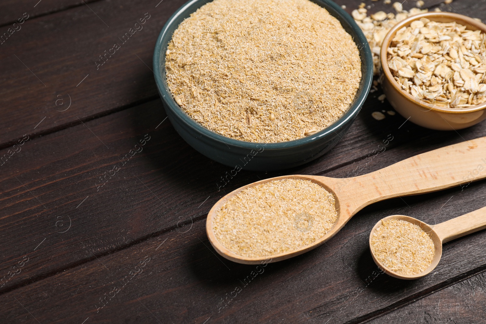 Photo of Oat bran and flakes on wooden table, closeup. Space for text