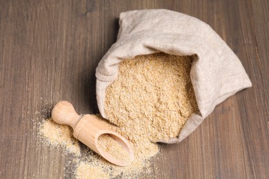 Photo of Oat bran in burlap bag and scoop on wooden table