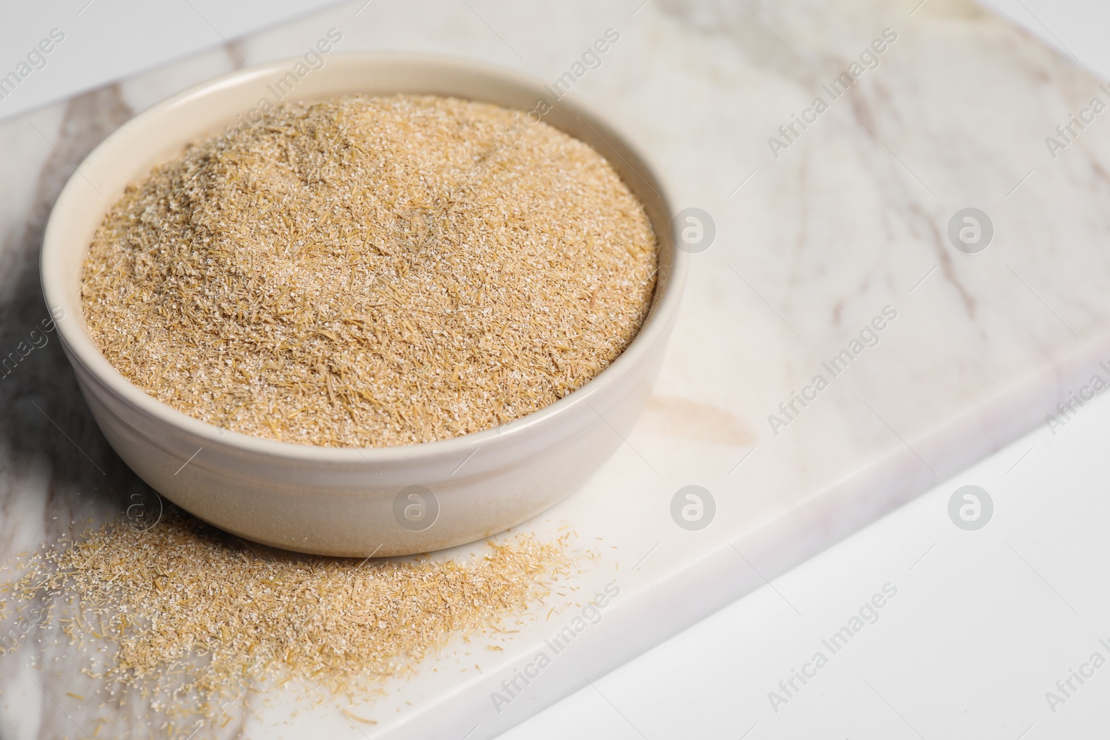 Photo of Oat bran in bowl on white table, closeup