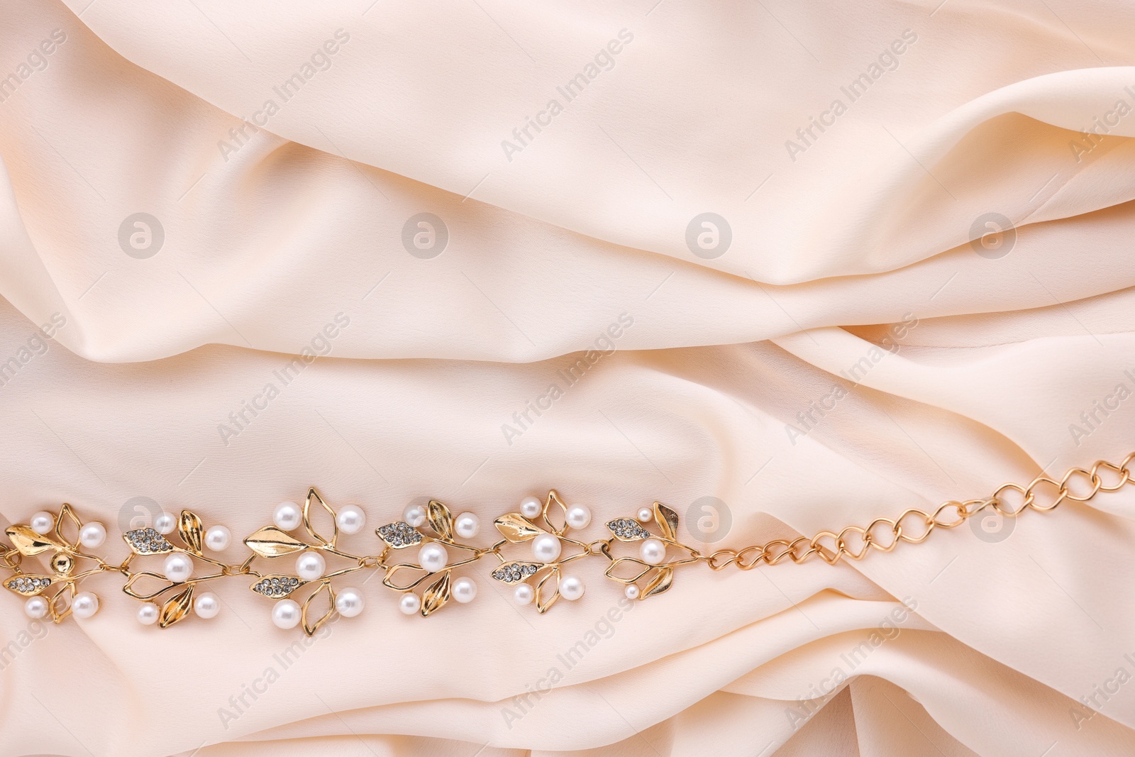 Photo of Beautiful bracelet with pearls on beige cloth, top view. Space for text