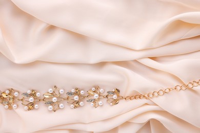 Photo of Beautiful bracelet with pearls on beige cloth, top view. Space for text