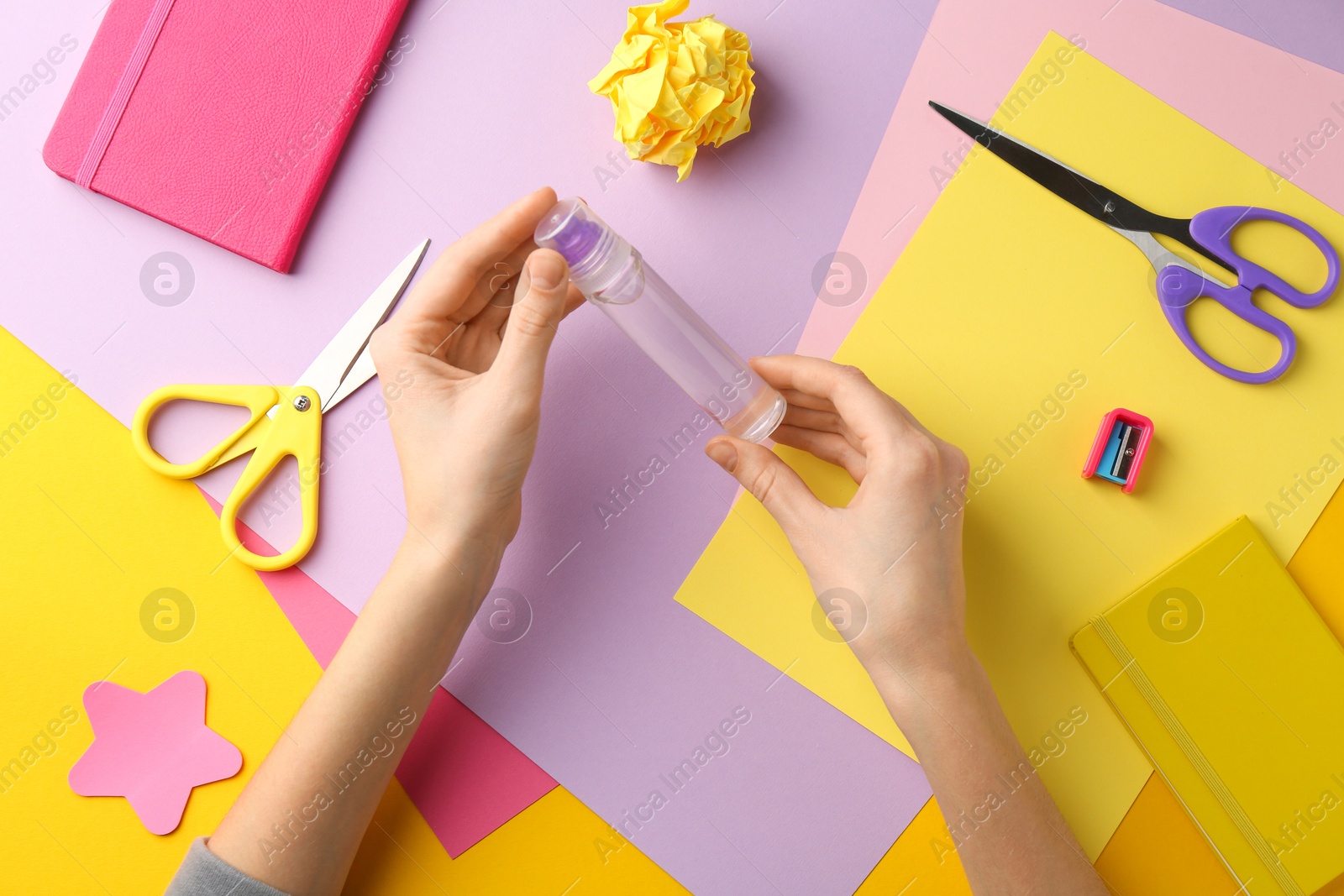 Photo of Woman with glue, scissors and colorful paper at table, top view