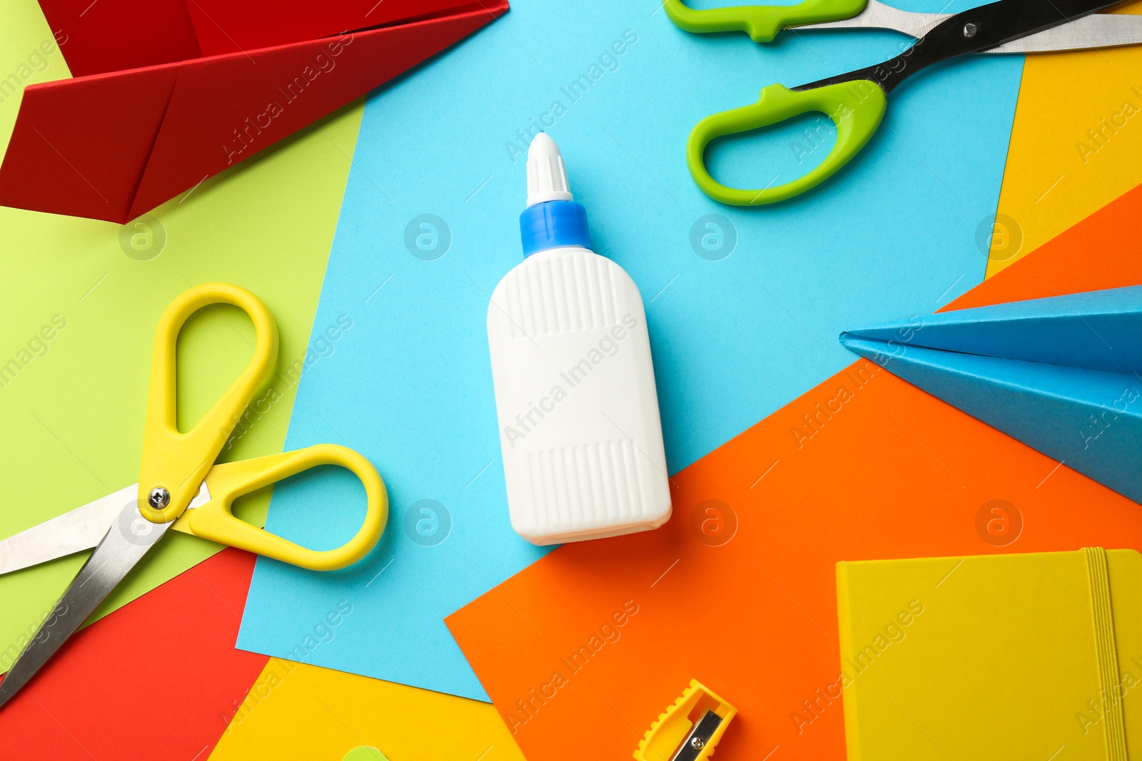 Photo of Flat lay composition with glue, scissors and other stationery on color background