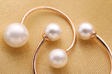 Photo of Beautiful pearl jewelry on golden silk, macro view