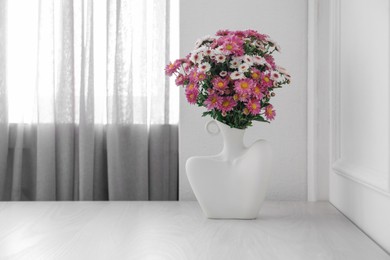 Photo of Stylish vase with beautiful flowers on white wooden table at home, space for text