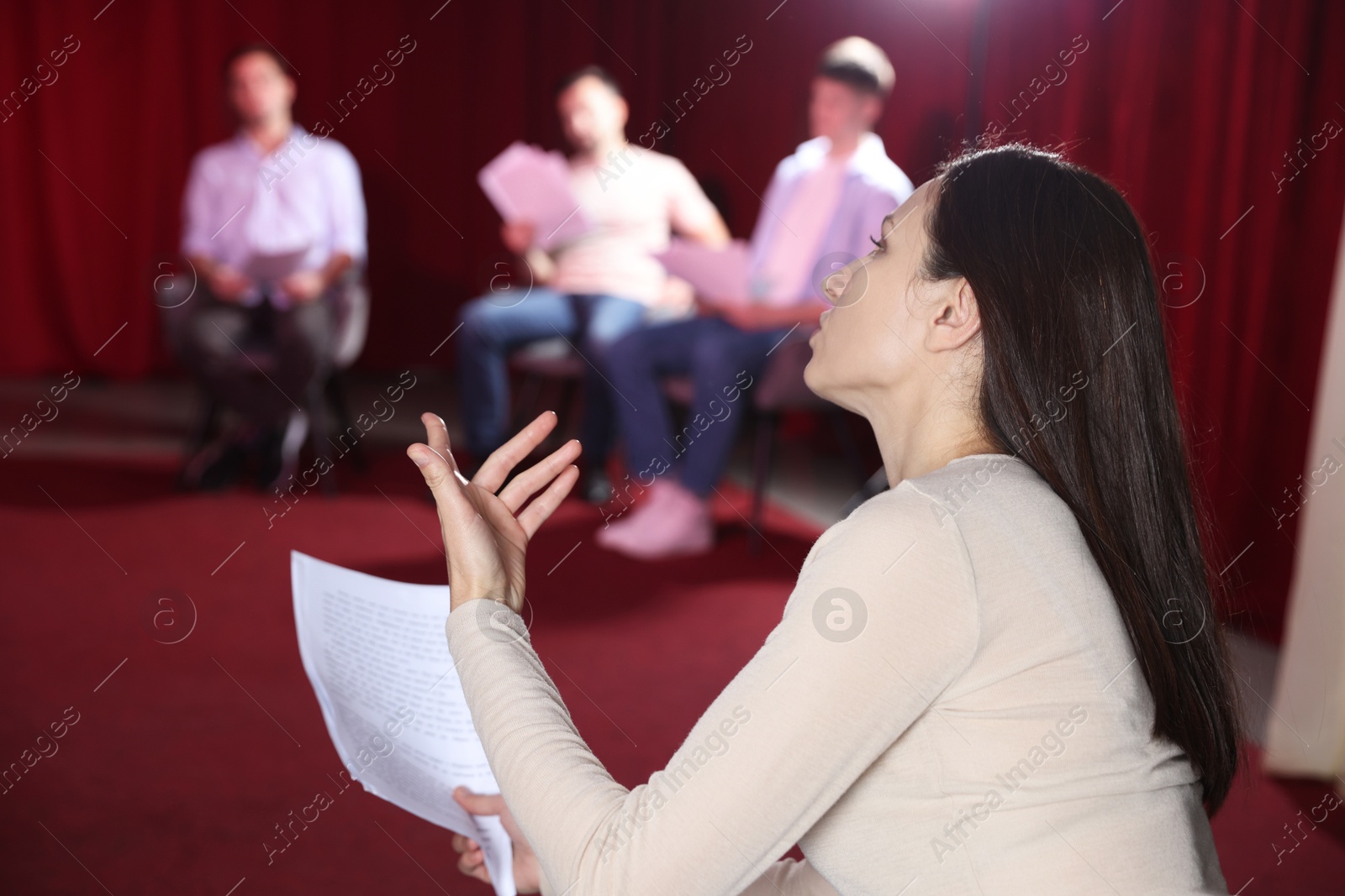 Photo of Professional actors with their scripts rehearsing in theatre