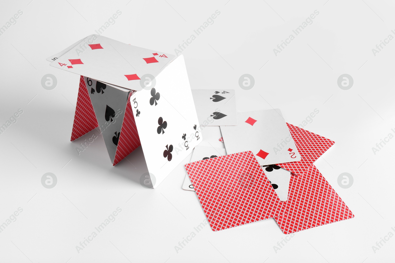 Photo of Collapsed house of playing cards on light background