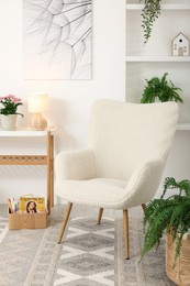 Photo of Soft armchair and houseplants in living room