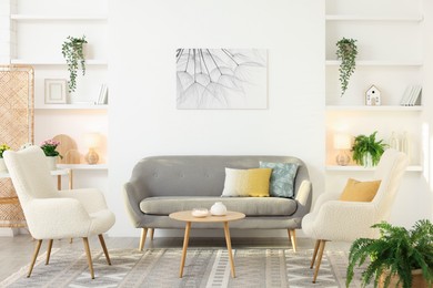 Photo of Beautiful armchairs, sofa and coffee table in living room. Interior design