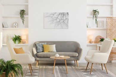 Photo of Beautiful armchairs, sofa and coffee table in living room. Interior design