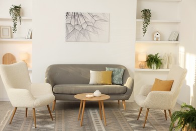 Photo of Beautiful armchairs, sofa and coffee table in living room. Interior design