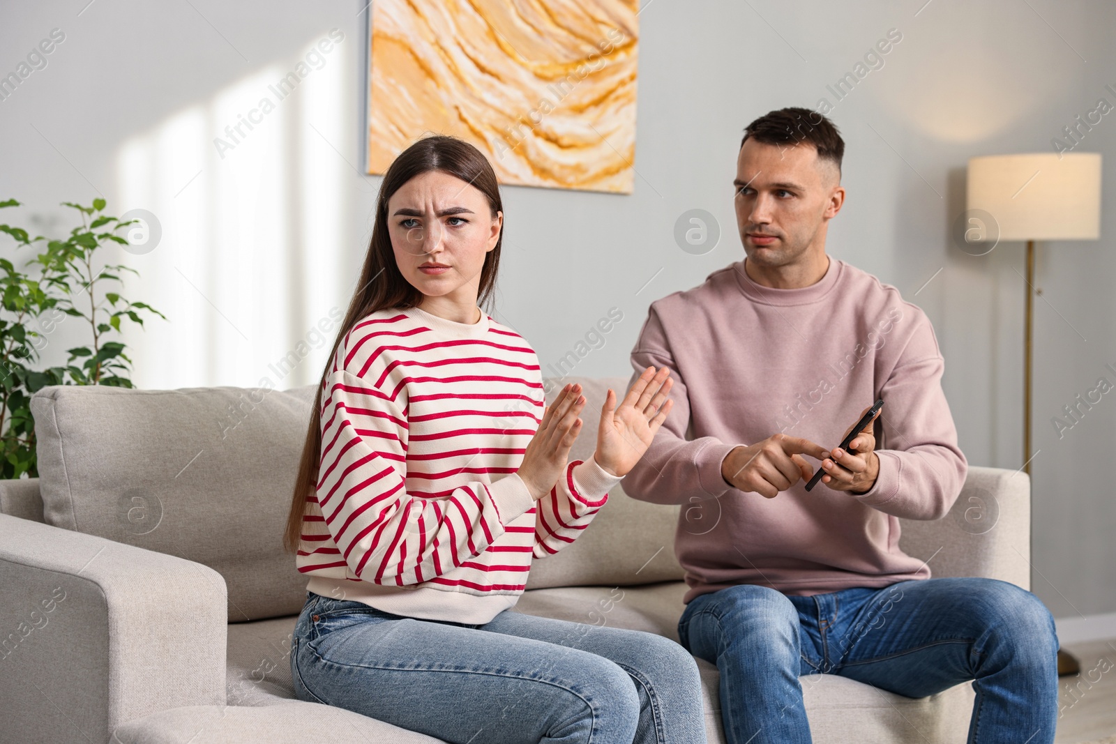 Photo of Husband showing smartphone with proofs to his unfaithful wife at home