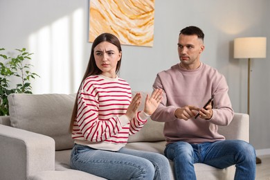 Photo of Husband showing smartphone with proofs to his unfaithful wife at home