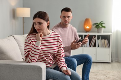 Photo of Upset woman ignoring her husband at home. Relationship problems