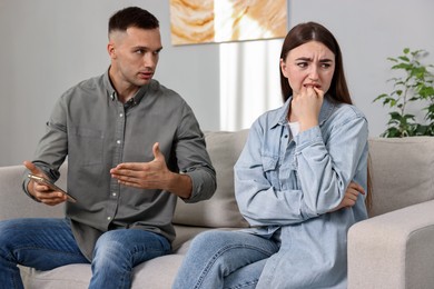 Husband showing smartphone with proofs to his unfaithful wife at home