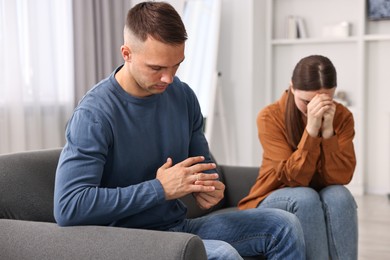 Photo of Offended couple ignoring each other at home