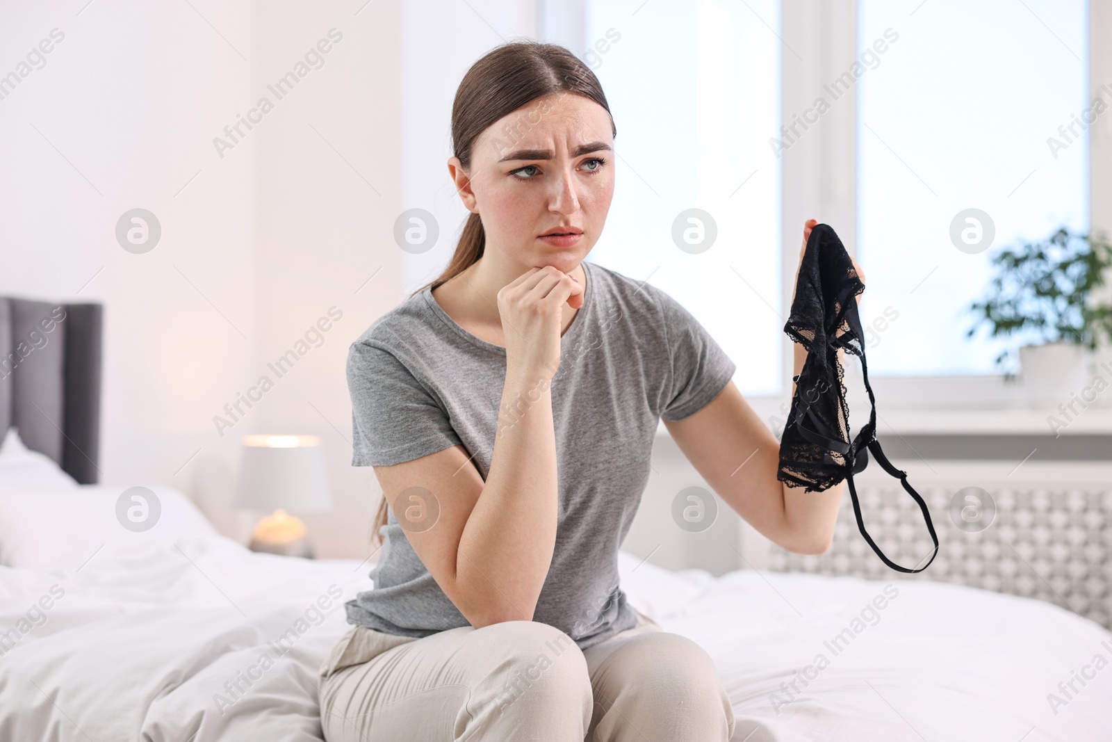 Photo of Frustrated wife finding mistress bra in bedroom