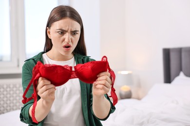 Photo of Surprised wife finding mistress bra in bedroom. Space for text