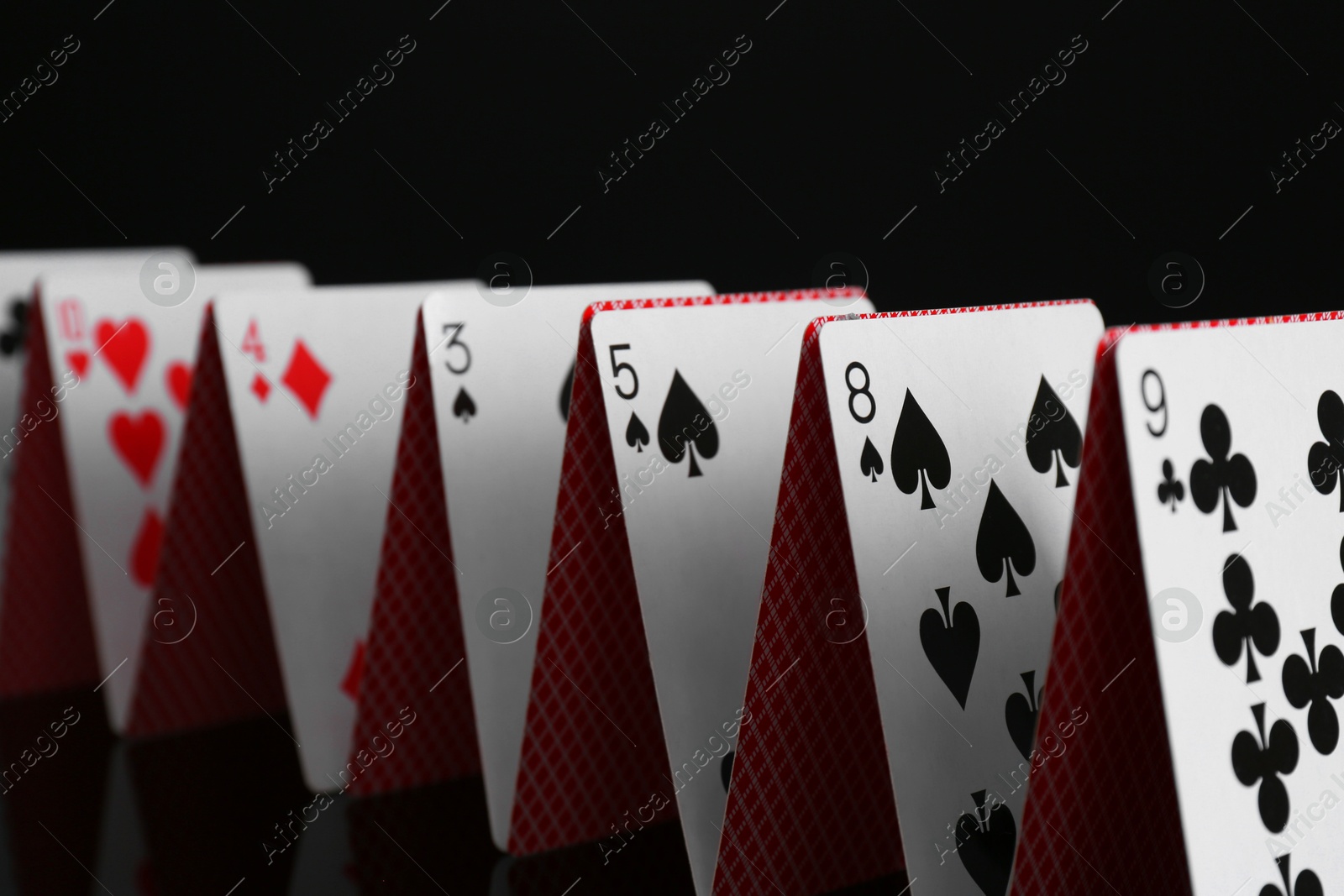 Photo of Row of playing cards on black background, closeup