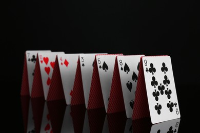 Photo of Row of playing cards on black mirror surface, closeup