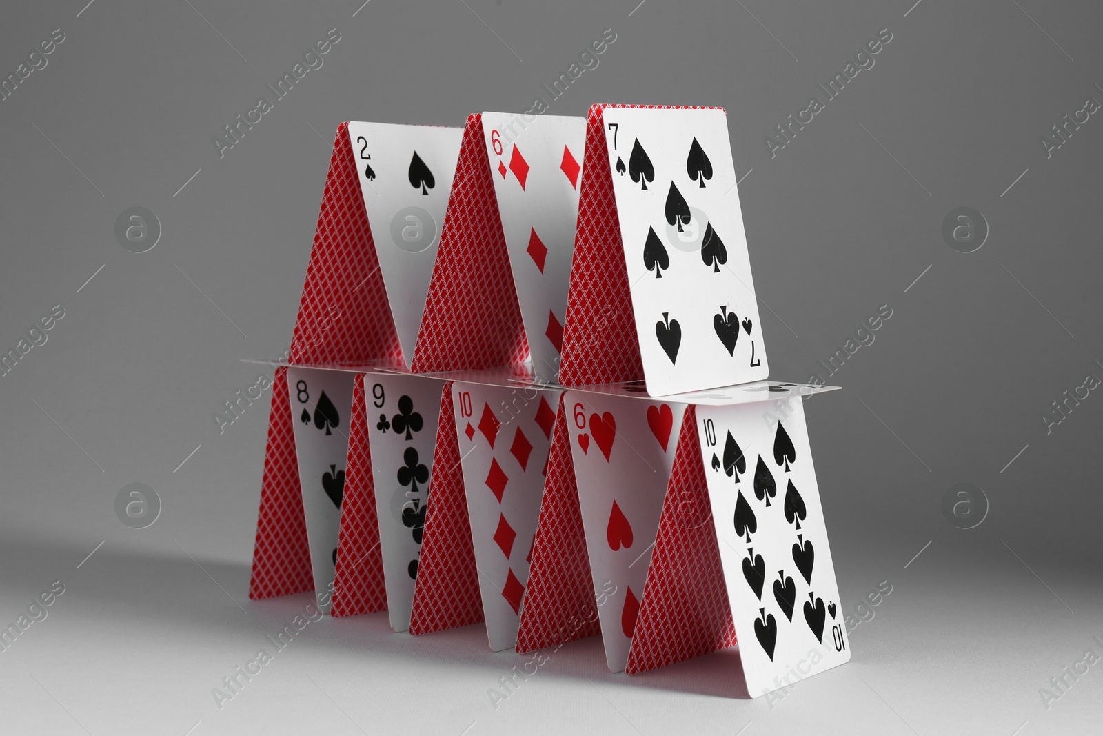 Photo of House of playing cards on grey background