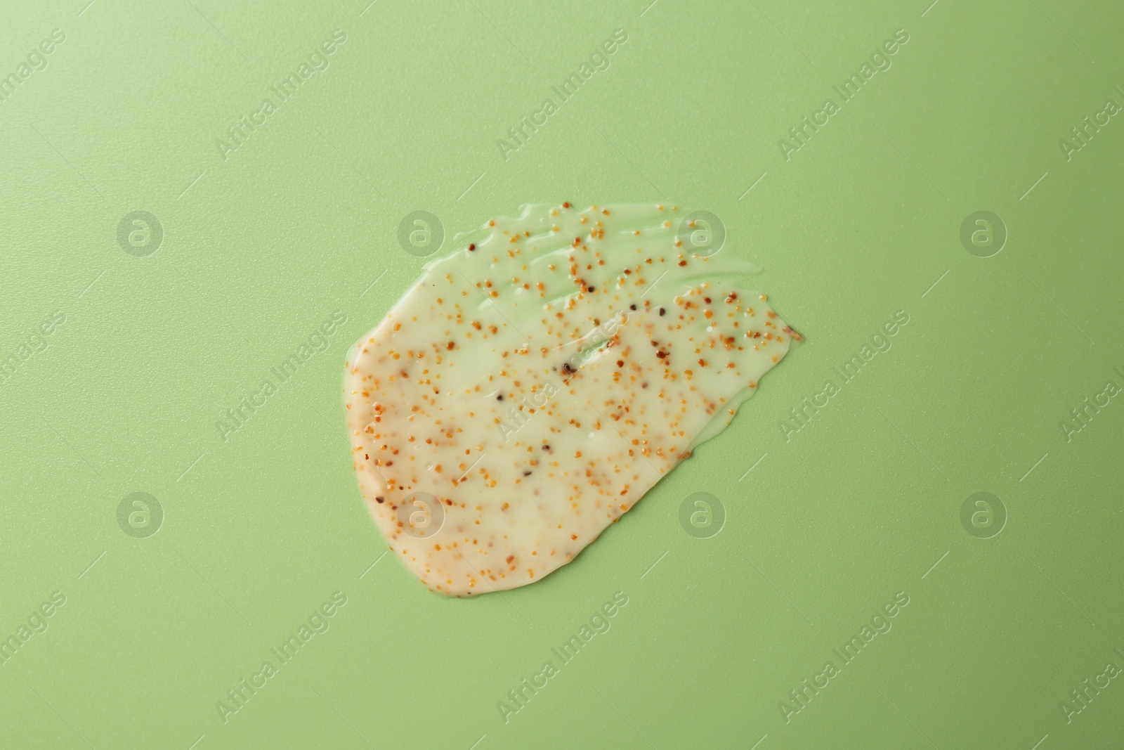 Photo of Smear of body scrub on green background, top view