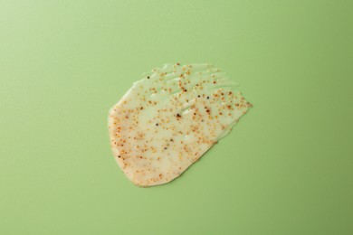 Photo of Smear of body scrub on green background, top view