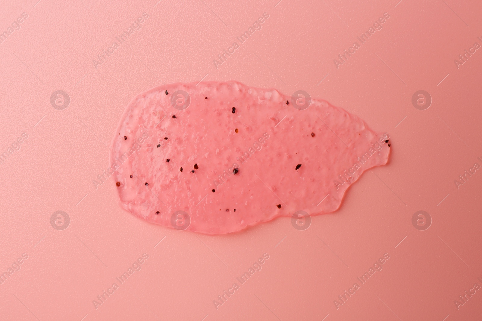 Photo of Smear of body scrub on light pink background, top view