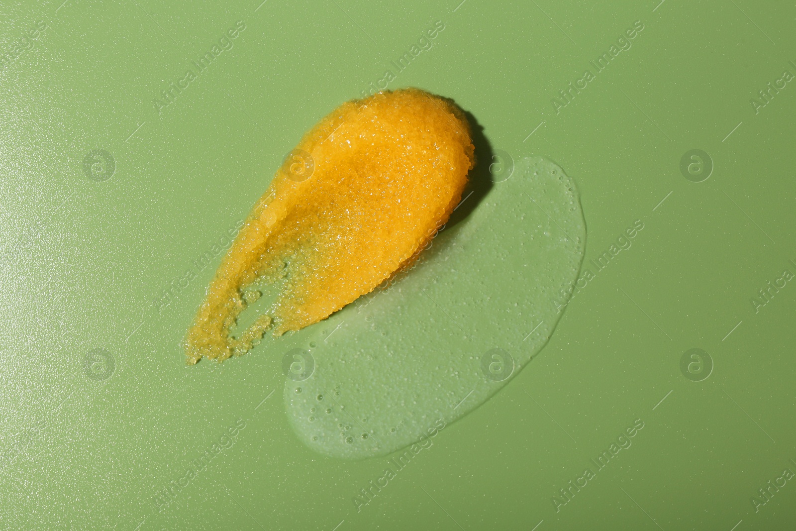 Photo of Smears of body scrubs on green background, top view