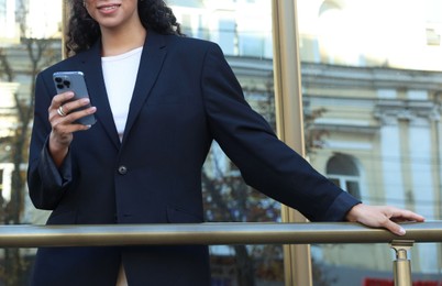 Photo of Young woman with phone wearing stylish suit outdoors, closeup