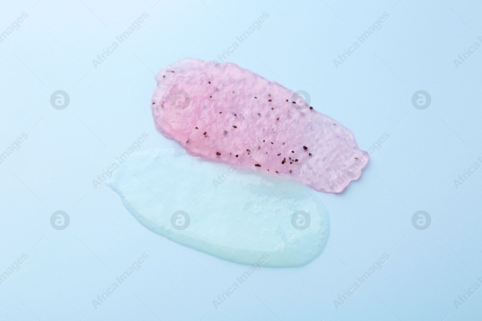 Photo of Smears of body scrubs on light blue background, closeup