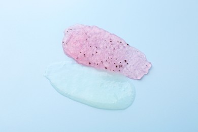 Photo of Smears of body scrubs on light blue background, closeup