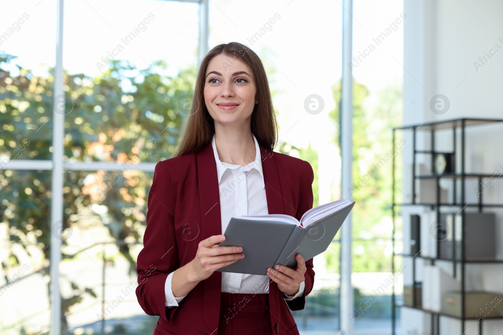 Photo of Portrait of young woman with book wearing stylish suit indoors