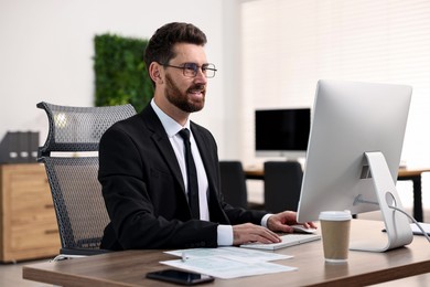 Photo of Man working on computer at table in office