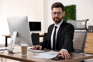 Photo of Man working on computer at table in office