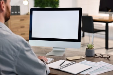 Photo of Man working on computer at table in office, closeup