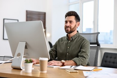 Photo of Man working on computer at table in office