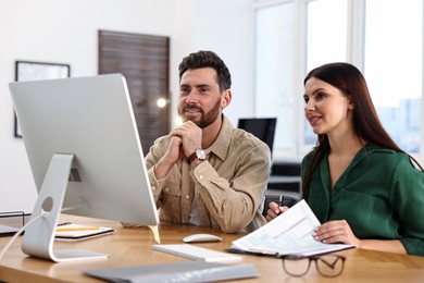 Photo of Colleagues working with computer at desk in office